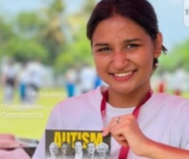A photo from the Obai Mamai campaign showing a young woman holding a leaflet about autism.